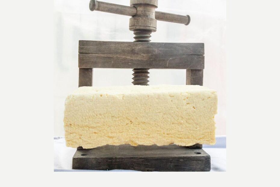 Tofu is being pressed with a wooden press