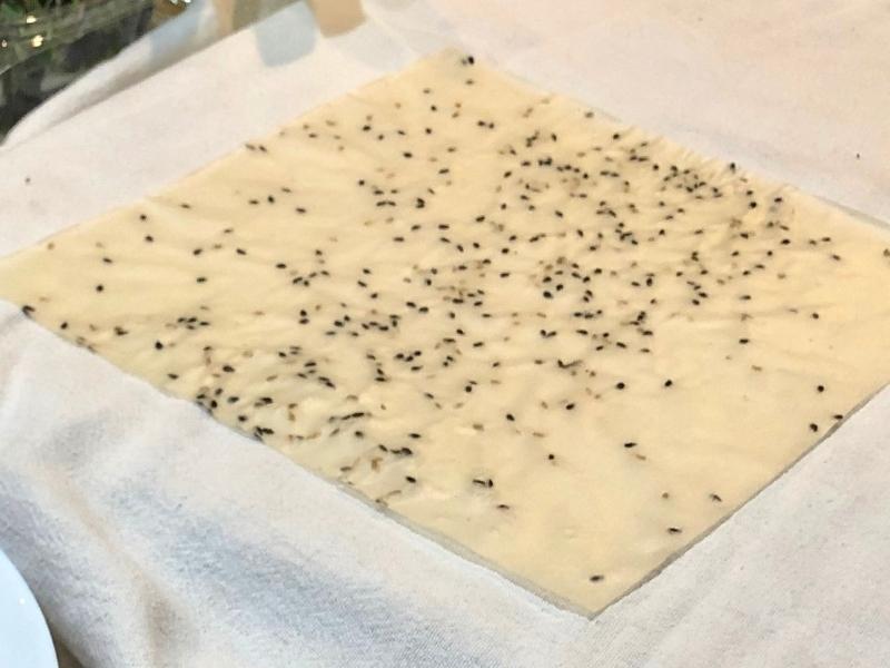 White sheet with black sesame seeds on a white cloth