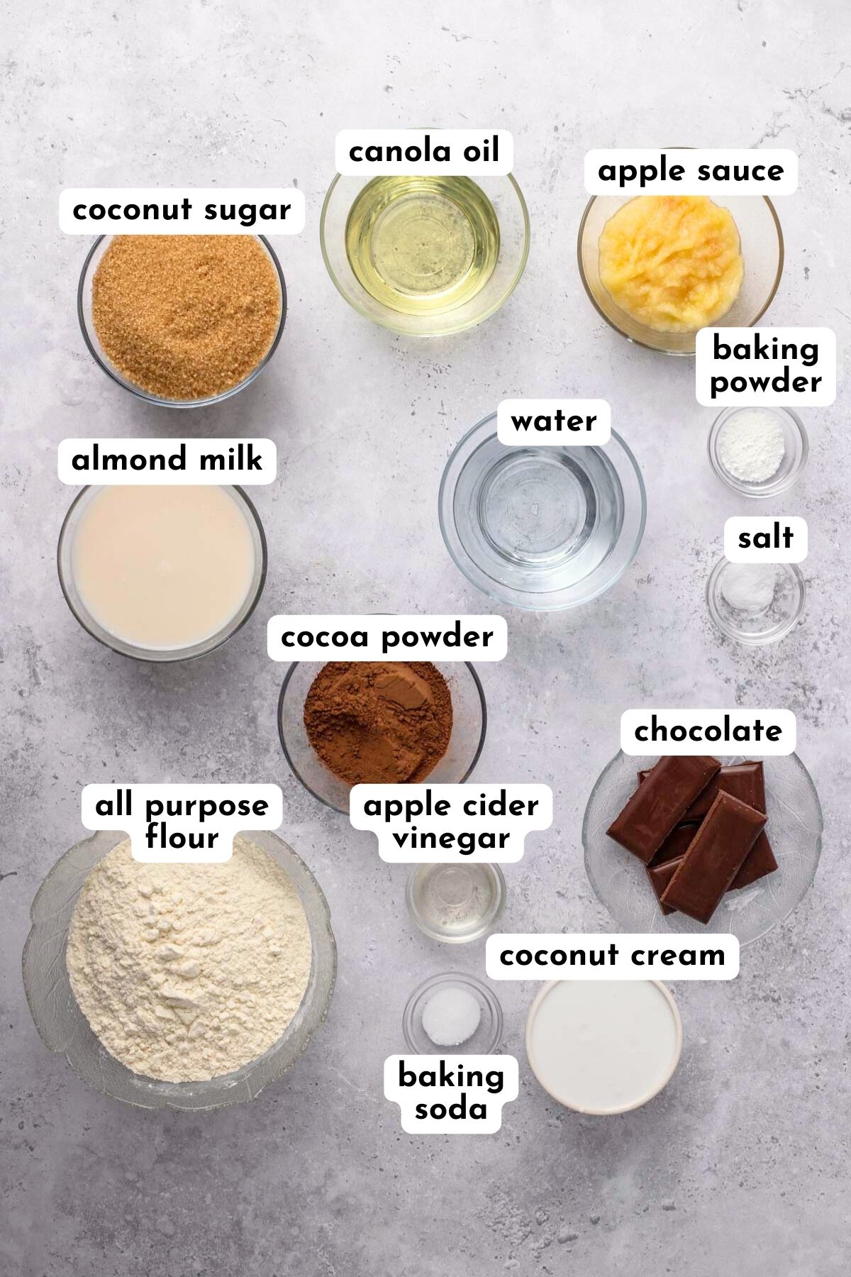 Ingredients of chocolate cake in small glass bowls from flour to oil. 