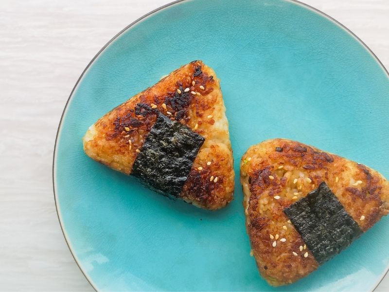 2 triangle shaped rice balls with nori stripes fried until brown and crispy