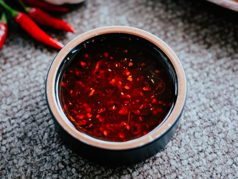 Small black bowl with vibrant red sauce with flakes