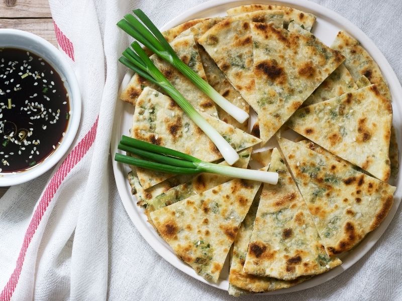 Large pancake cut as pizza topped with scallions