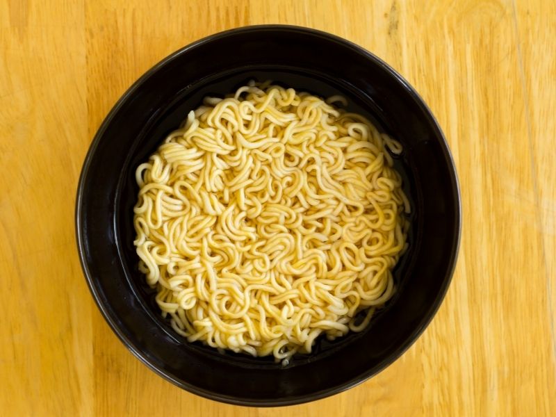 Yellow thin noodles in a black bowl