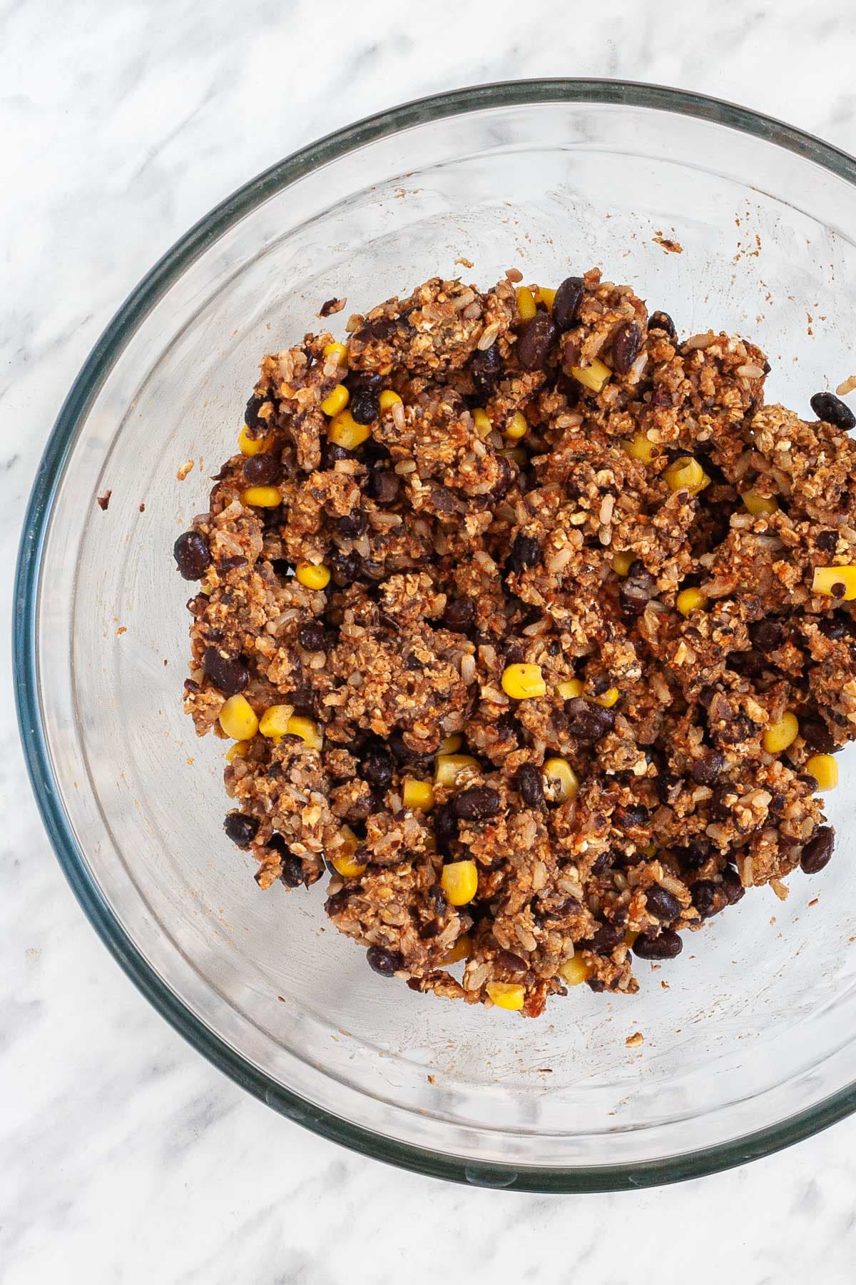Brown crumbly textured mix with sweet corn and black beans in a glass bowl.