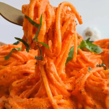 Vibrant orange sauce in spaghetti. A fork is lifting some of the pasta up.