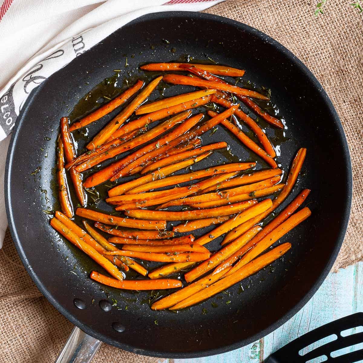 Frying pan with matchstick carrots in a glaze.
