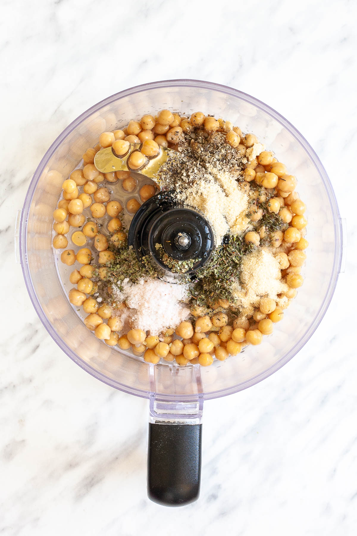 A food processor with chickpeas, spices and herbs