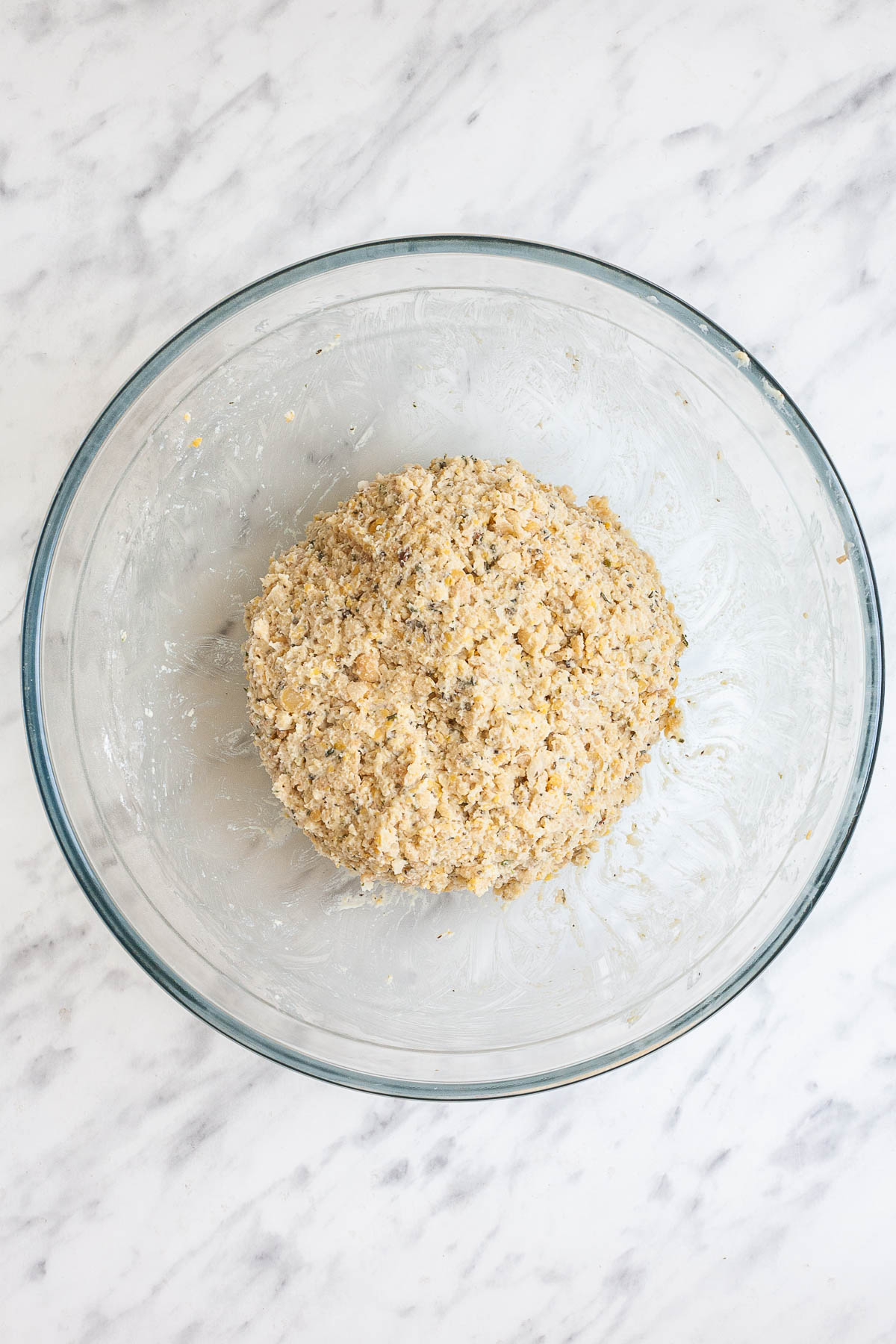 A glass bowl with a ball of sticky patty dough. 