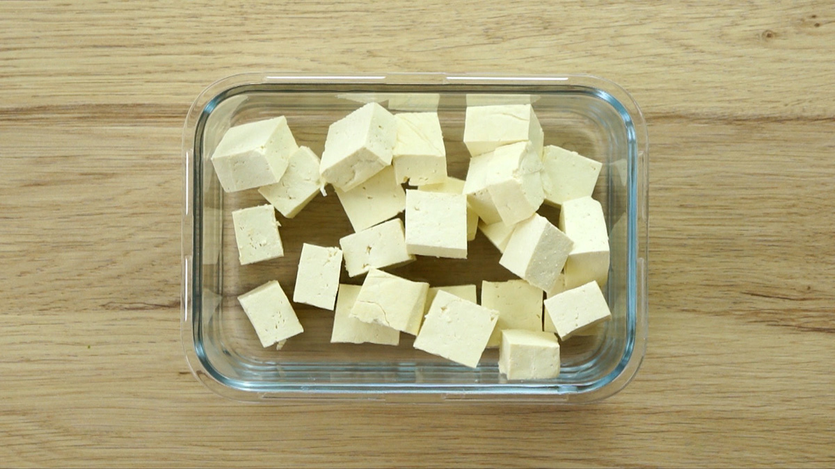 White raw tofu cubes in a glass container.