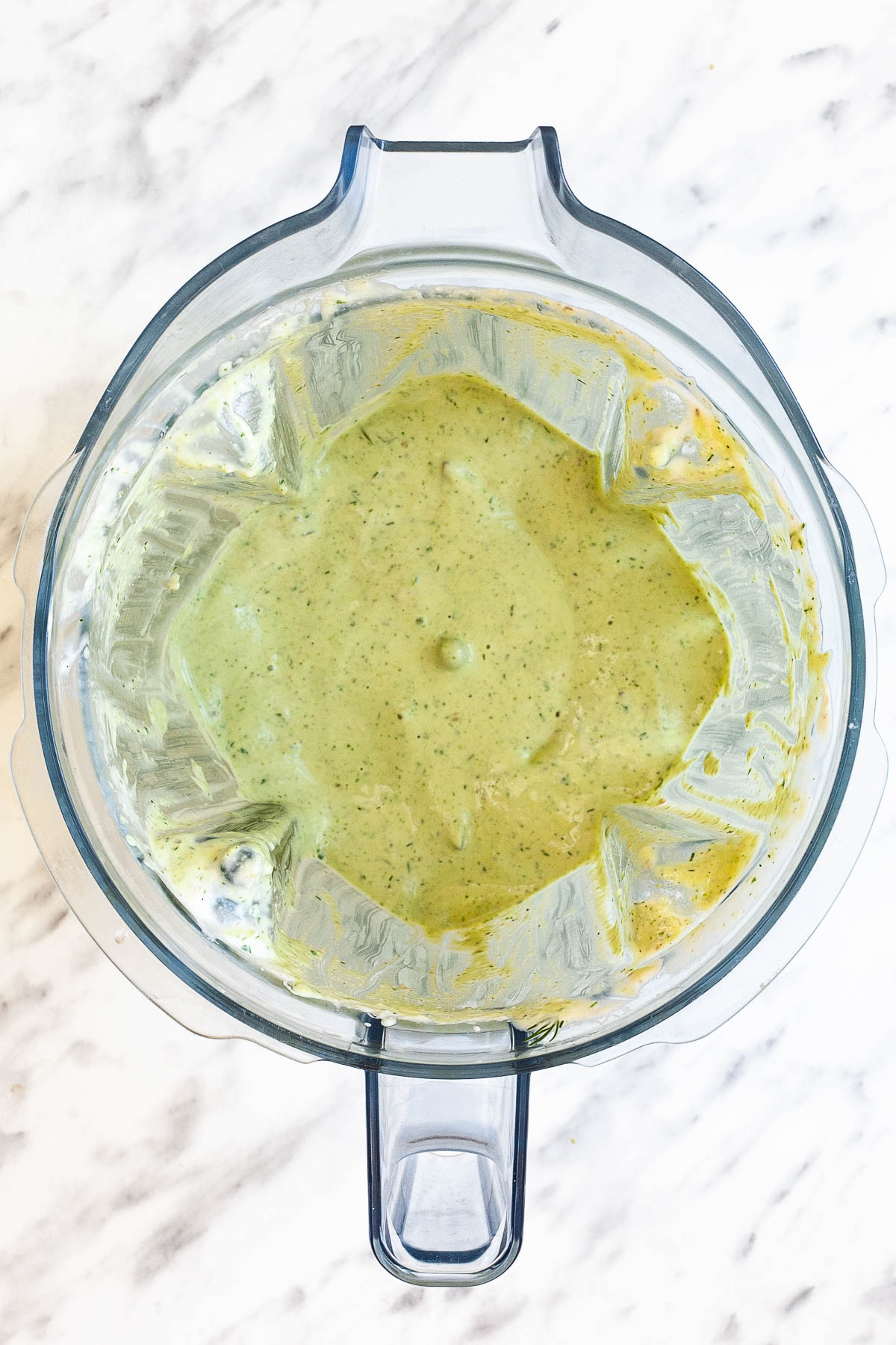 A blender from above with a creamy green sauce.