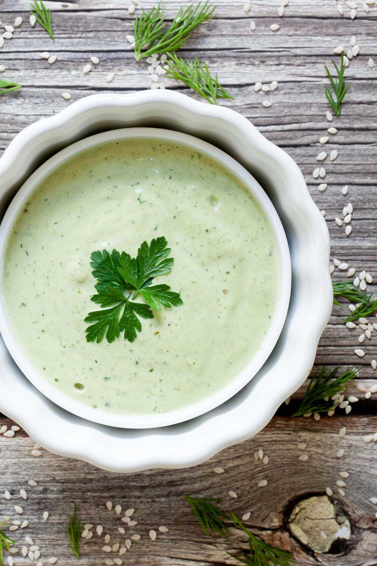 Light green sauce in a white bowl decorated with parsley and dill