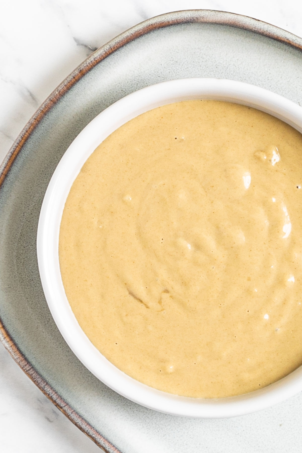 Creamy light brown sauce in a white shallow bowl.