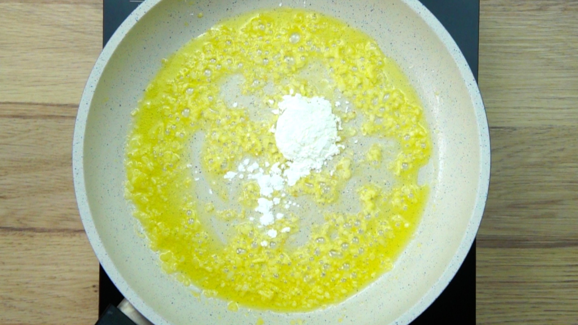 Melted butter, chopped onions, garlic and a small heap of white powder in a white frying pan