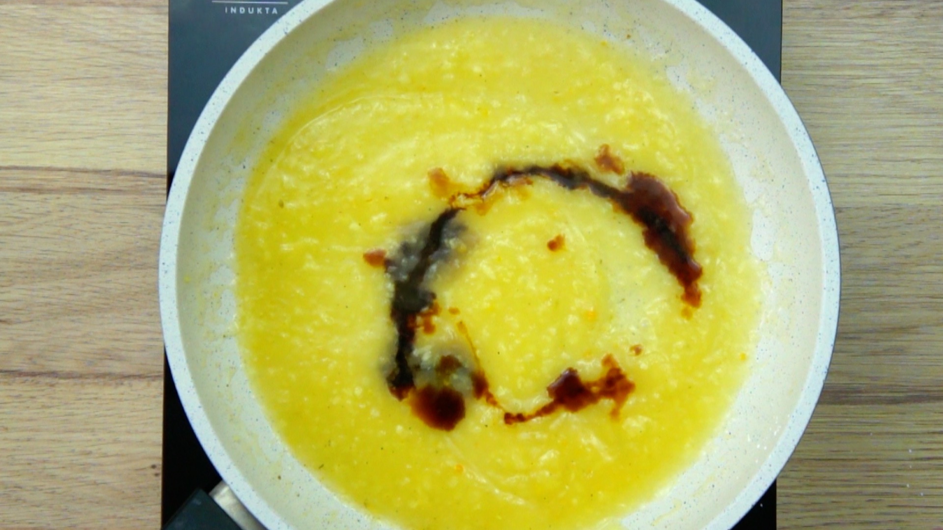 Dark brown swirl in yellow liquid in a frying pan.