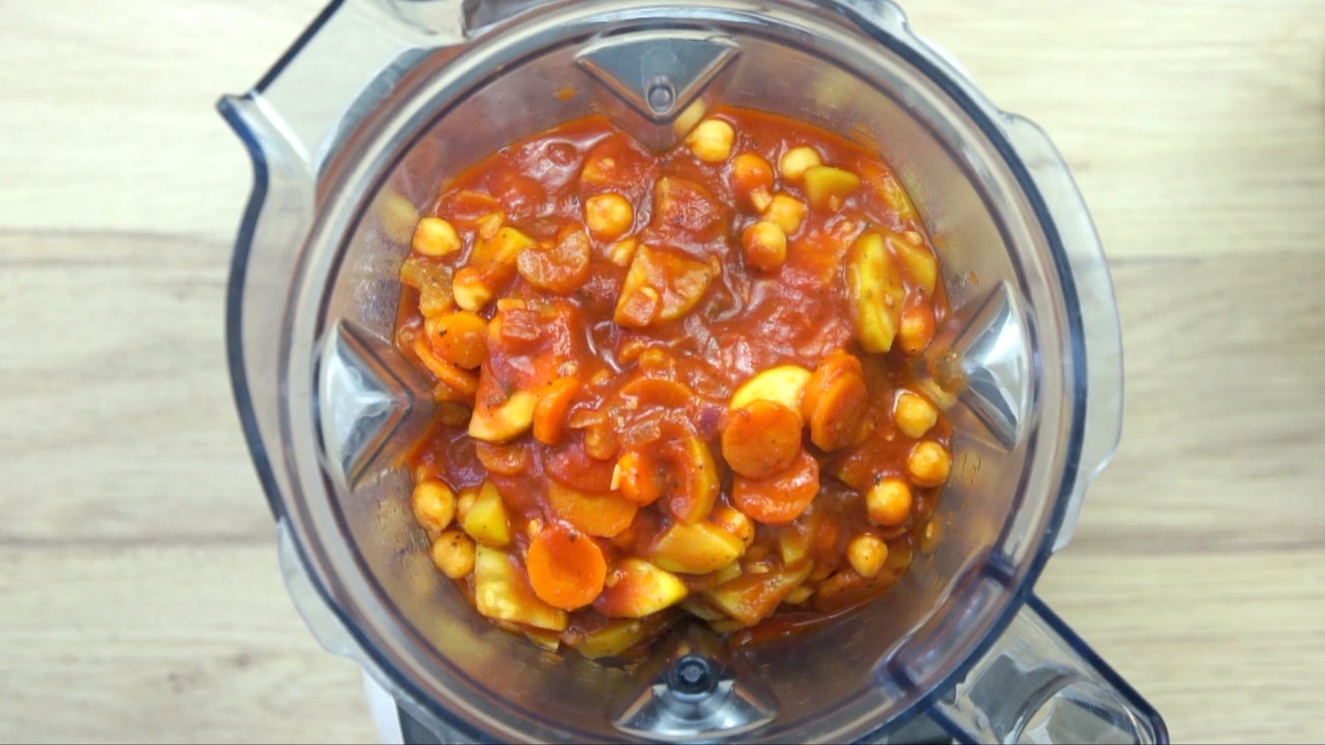 Veggie chunks covered with red tomato sauce in a blender.