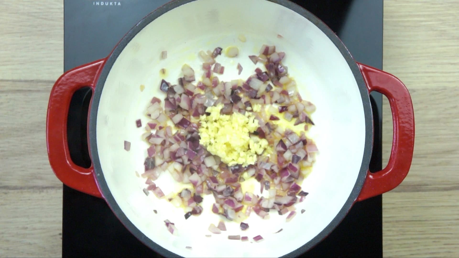 Chopped onion and garlic in a white red enamelled Dutch oven.