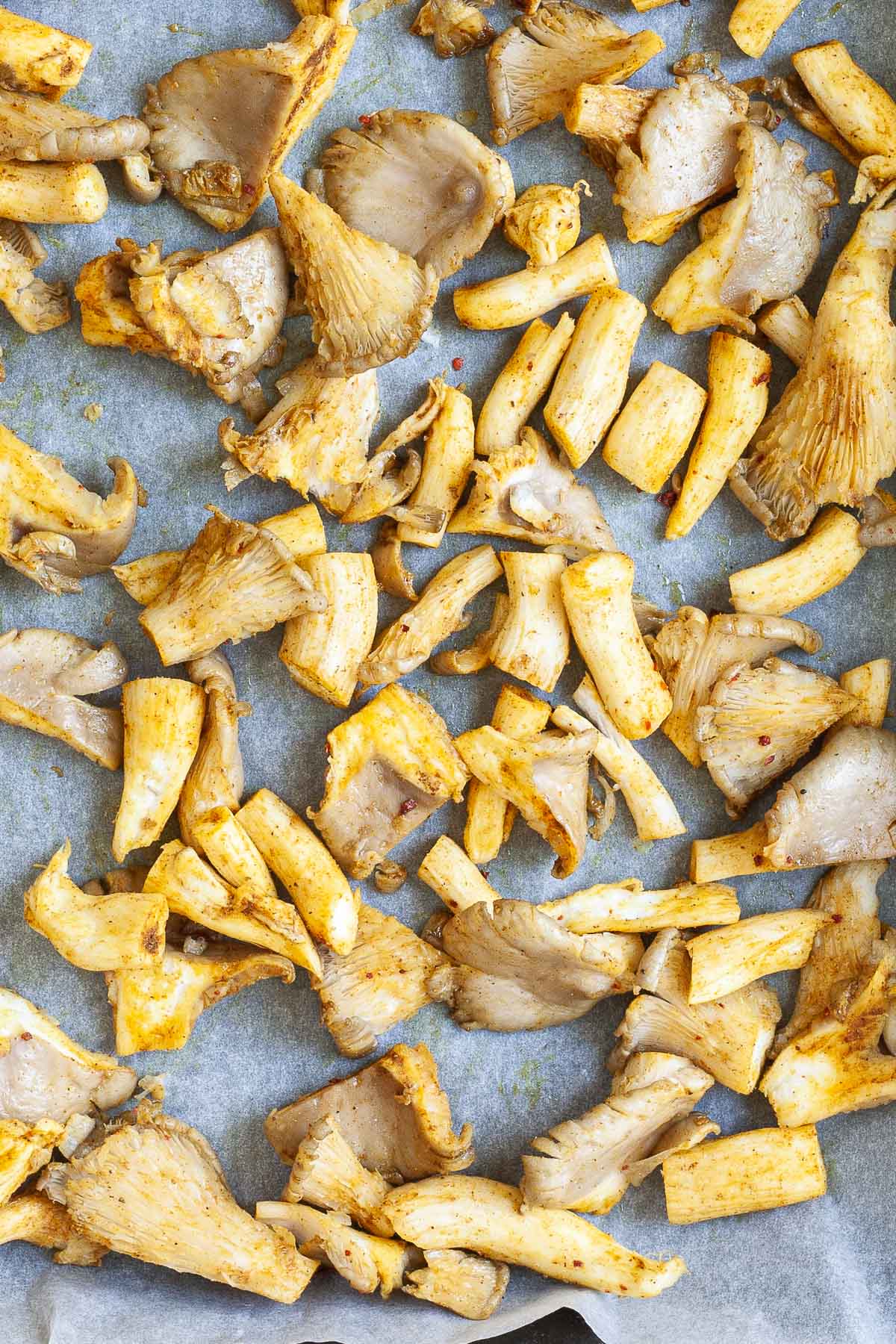 Yellowish raw mushroom shreds on a parchment paper.