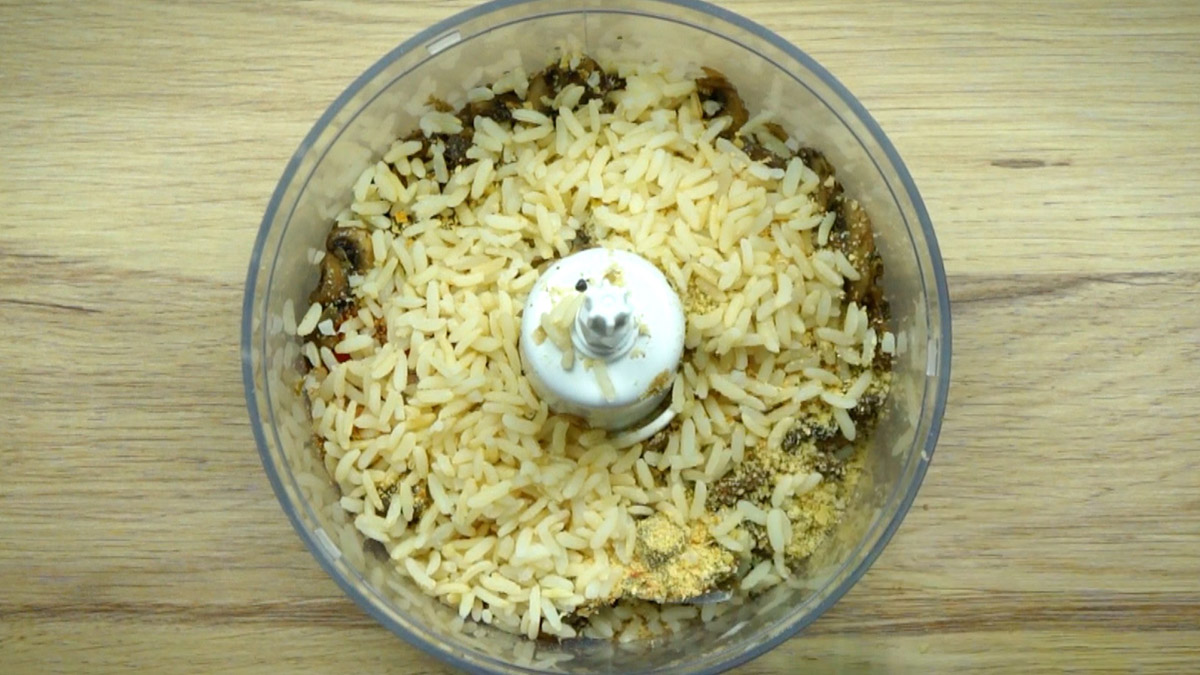Food processor with brown mushroom slices and lots of rice.