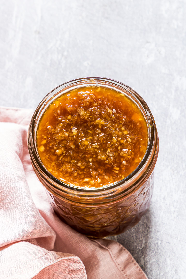 A chunky golden brown sauce in a small glass jar.