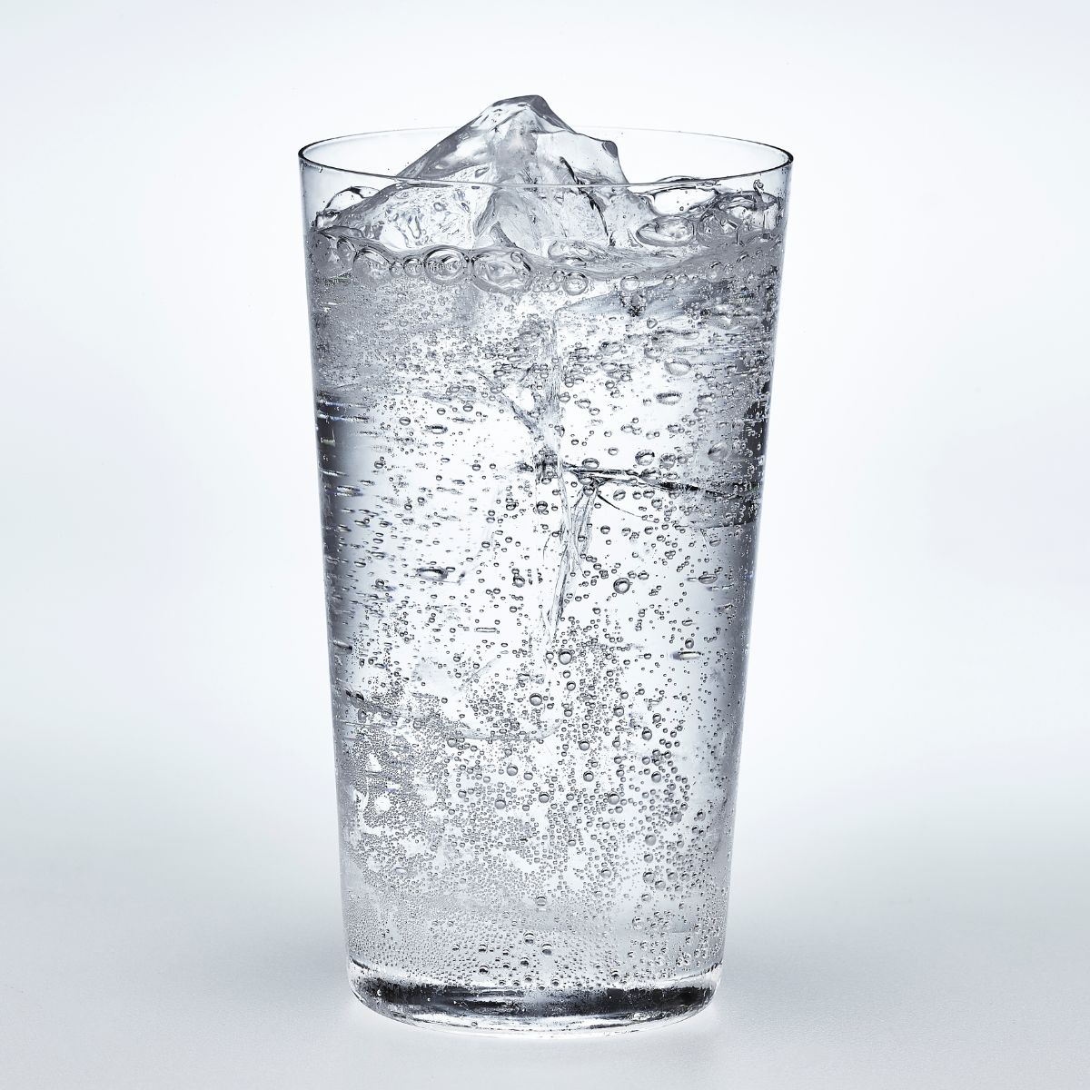 A glass of sparkling water in a white surface. 