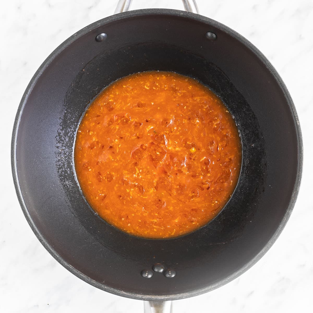 A chunky red sauce in a wok.