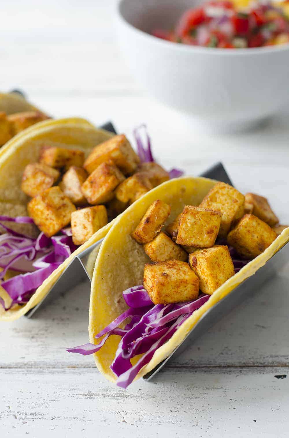 Hard tacos with yellow marinated tofu cubes and red cabbage slices.