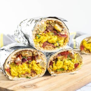 3 half tortillas wrapped in tin foil filled with sausage crumbles, diced potatoes, tofu scrambles, and avocado tomato salsa.