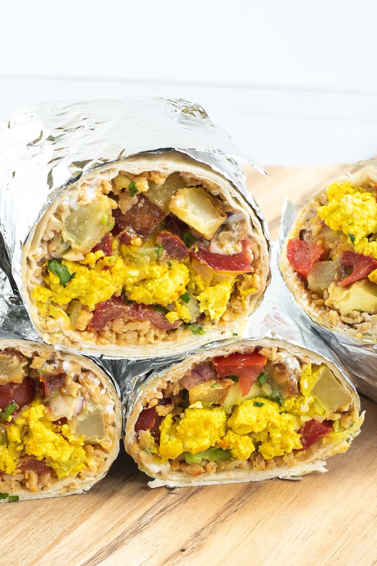 4 half tortillas wrapped in tin foil filled with sausage crumbles, diced potatoes, tofu scrambles, and avocado tomato salsa.