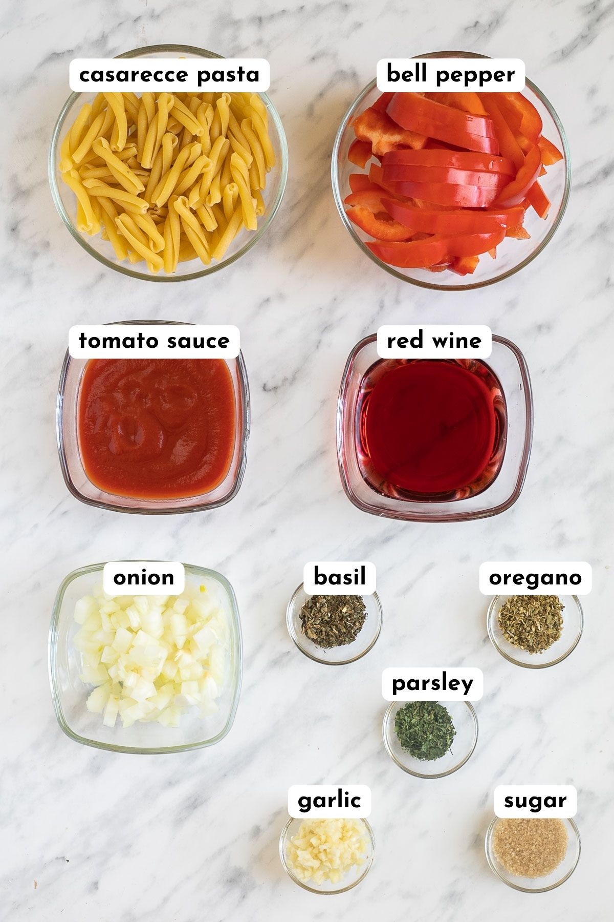 Ingredients of casarecce pasta with pepper sauce in small bowls like pasta, chopped bell pepper, tomato sauce, red wine, chopped onion, and different herbs and spices