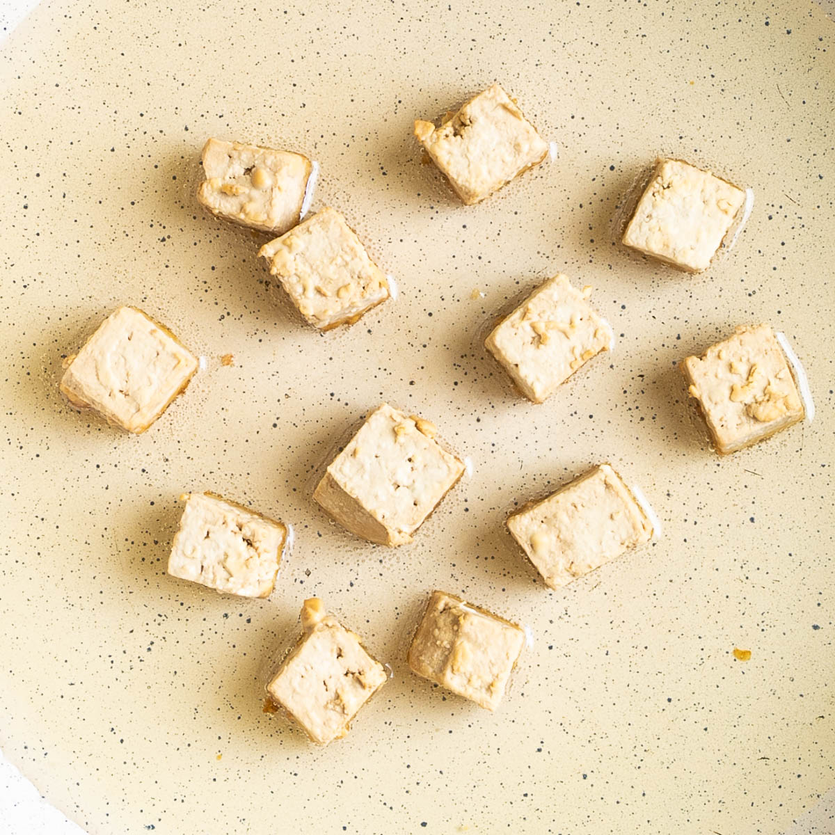 Light brown tofu cubes in a frying pan