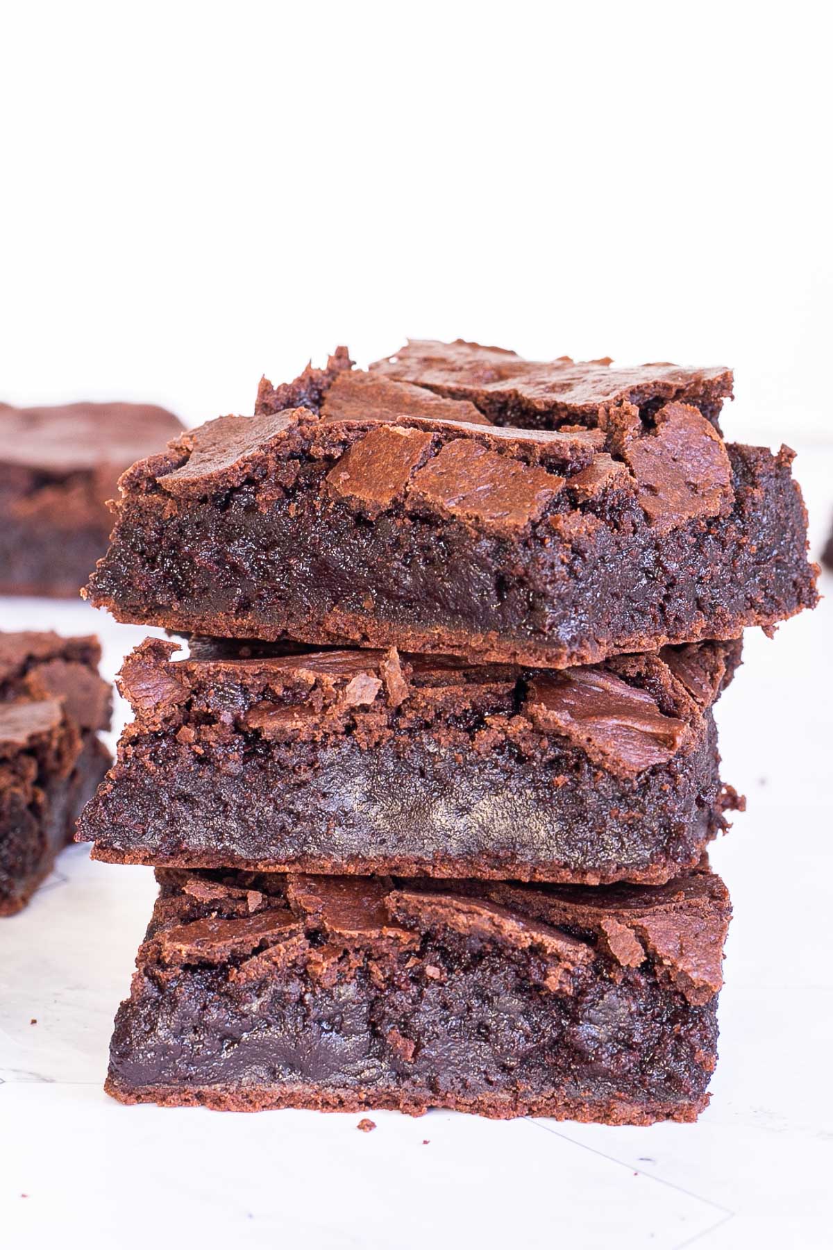 3 square brownies on top of each other with fudgy middle and crackly top.