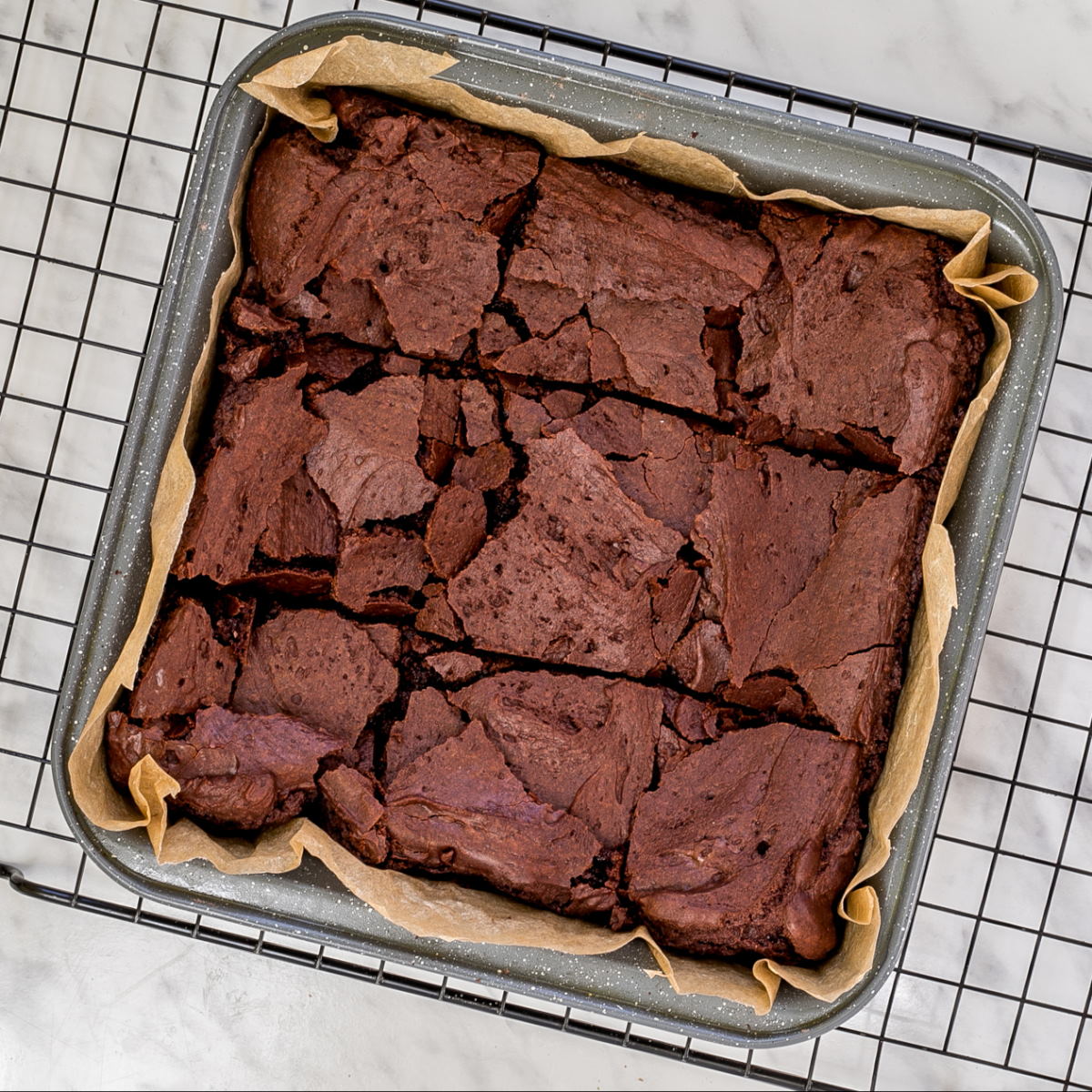 Square metal pan with crackly brownies cut into 9 squares.