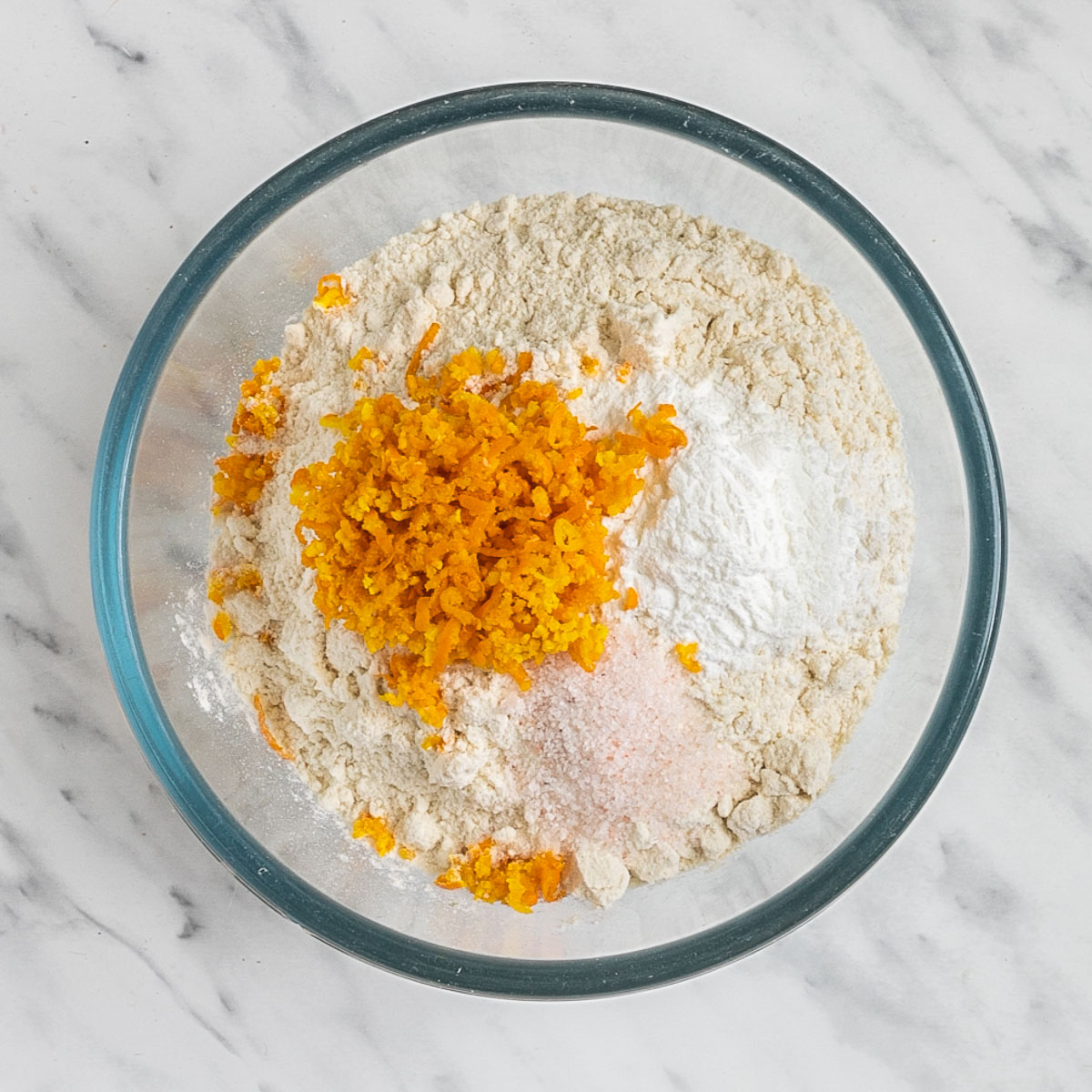 Glass bowl with flour, starch, salt, and grated orange zest