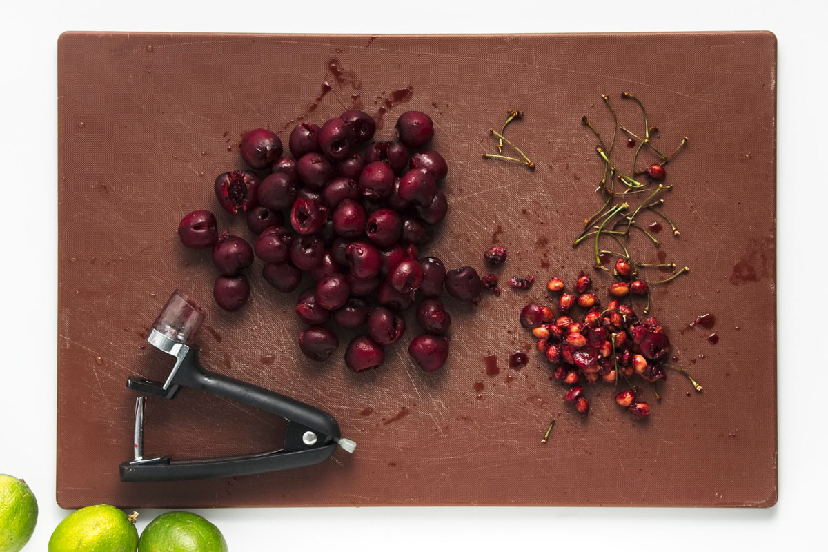 Cherries and pits on a brown board.