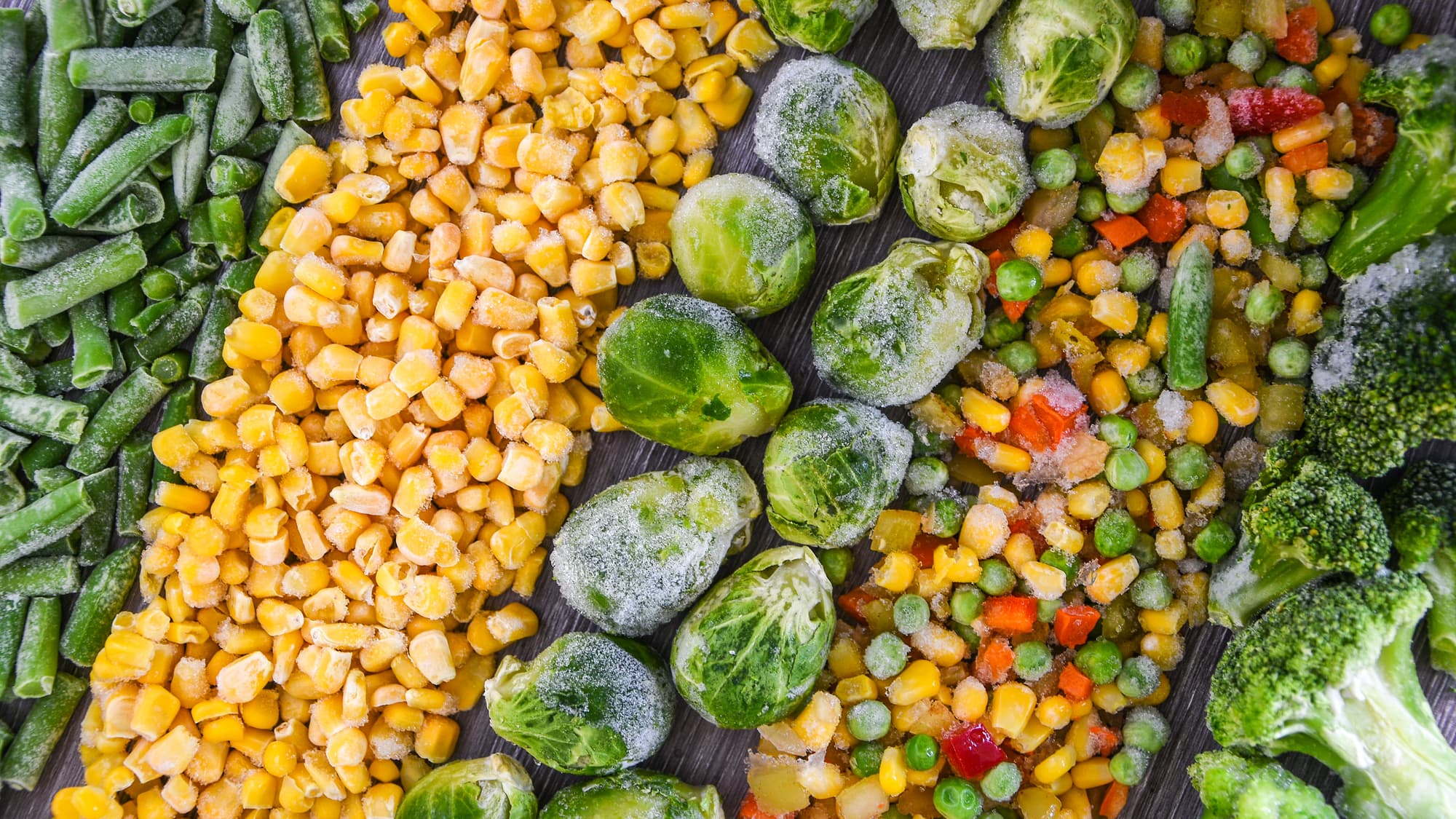 Frozen vegetables unpacked like corn, green beans, Brussels sprouts, broccoli, and mixed veggies