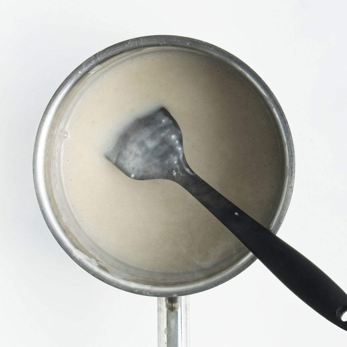 Saucepan with white liquid and a spatula