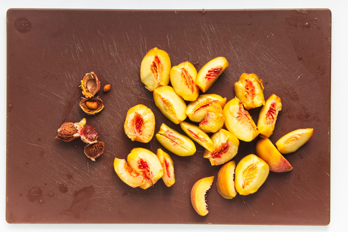 Sliced peaches and seeds on a brown cutting board.
