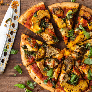 Pizza with summer squash, and caulifloer pieces sprinkled with fresh chopped herbs.