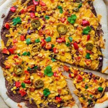 Pizza with bean puree, melted cheese, red pepper pieces, jalapeno slices and fresh cilantro.