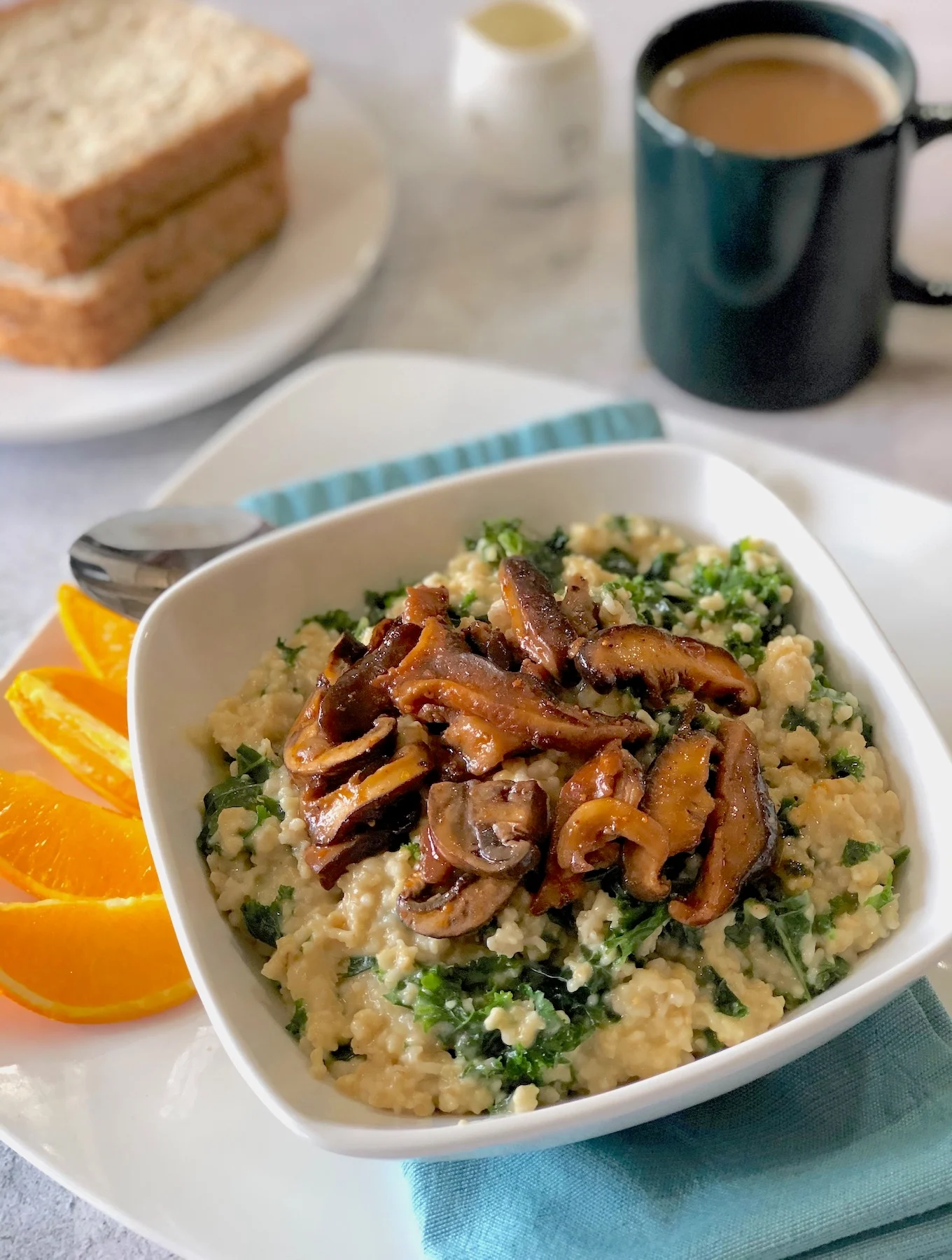 Steel cut oats and wilted spinach leaves in a gooey yellow sauce topped with crispy brown mushroom slices.