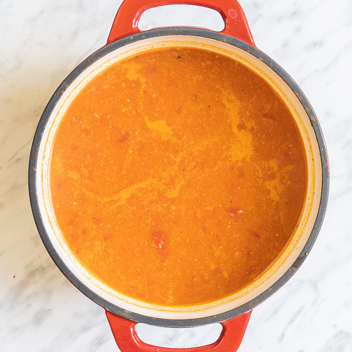 Orange soup in a white-red enameled Dutch oven.