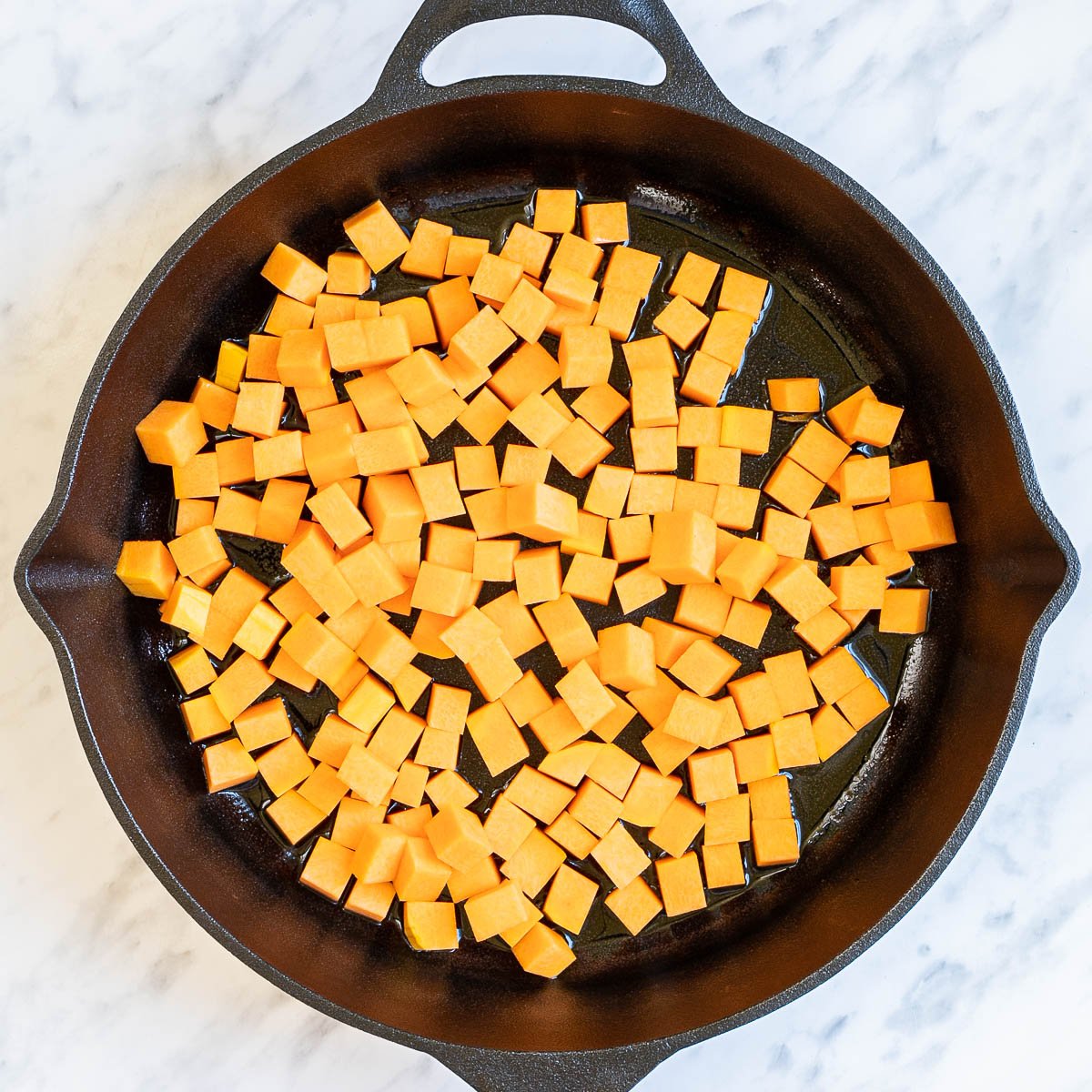 Cast iron skillet with orange squash cubes