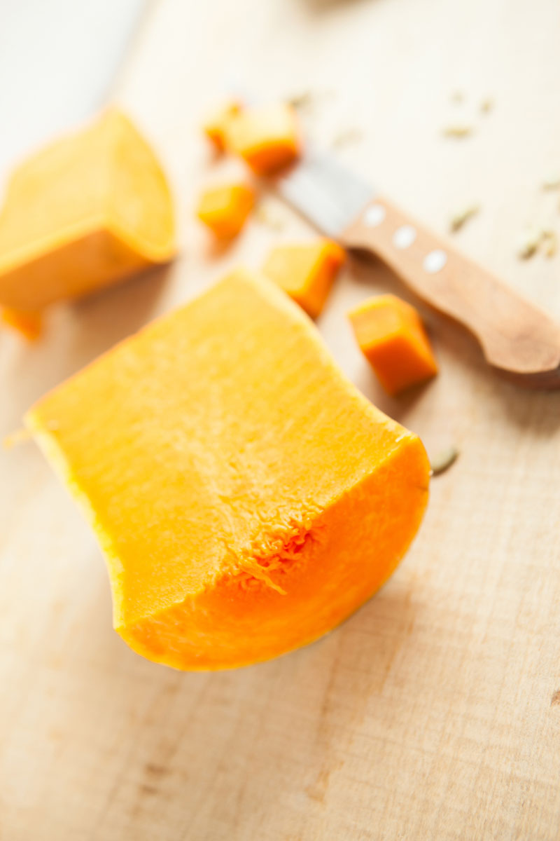 Half of the neck of a butternut squash on a wooden surface