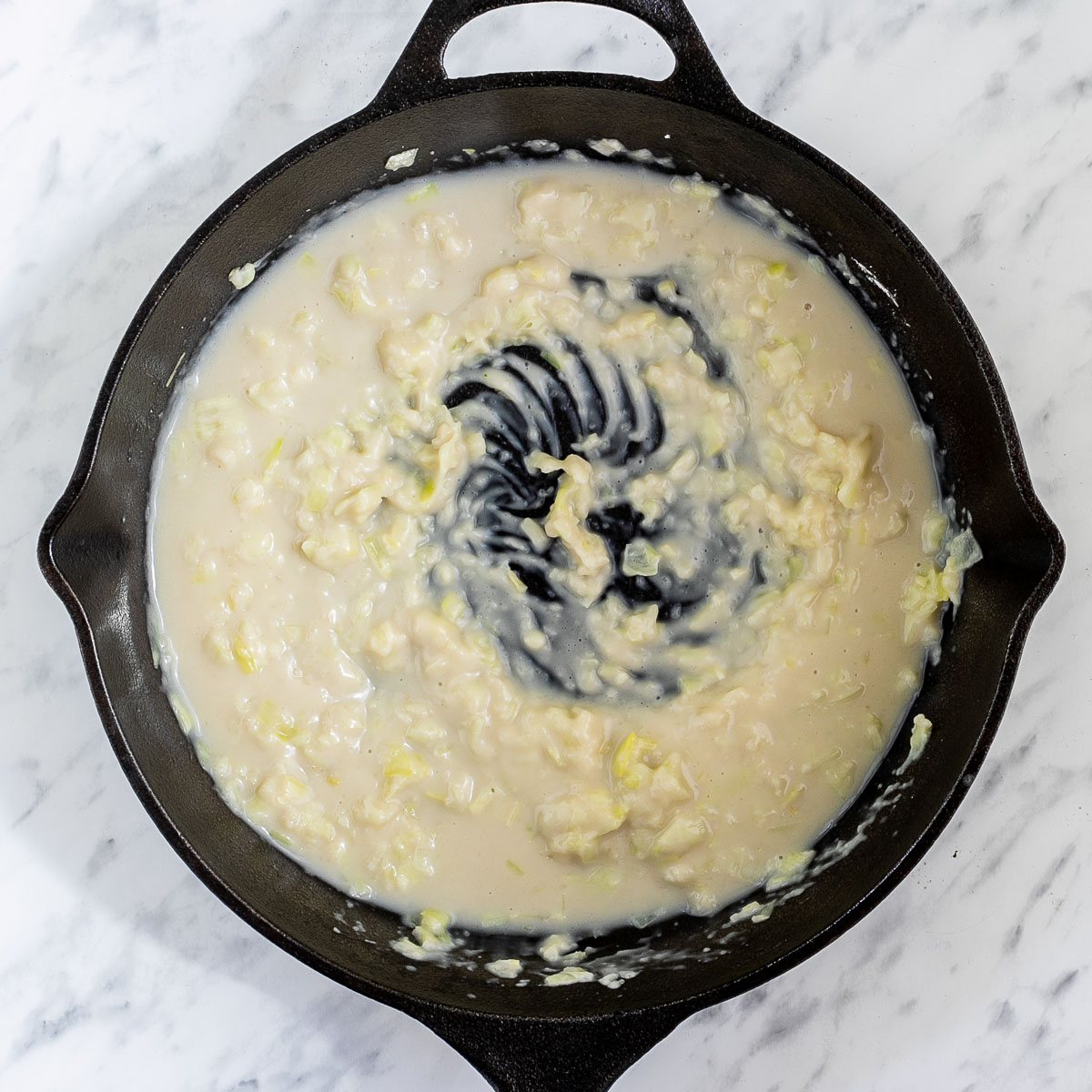 Black cast iron skillet with thick light brown sauce.