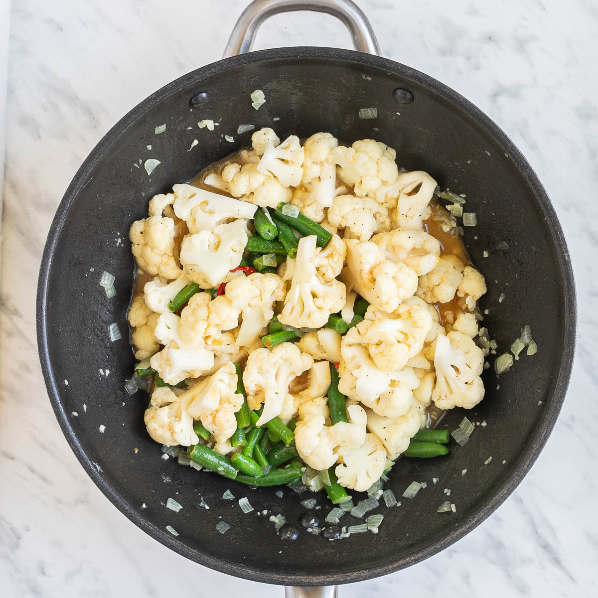 Wok with cauliflower florets and green beans in a light brown sauce