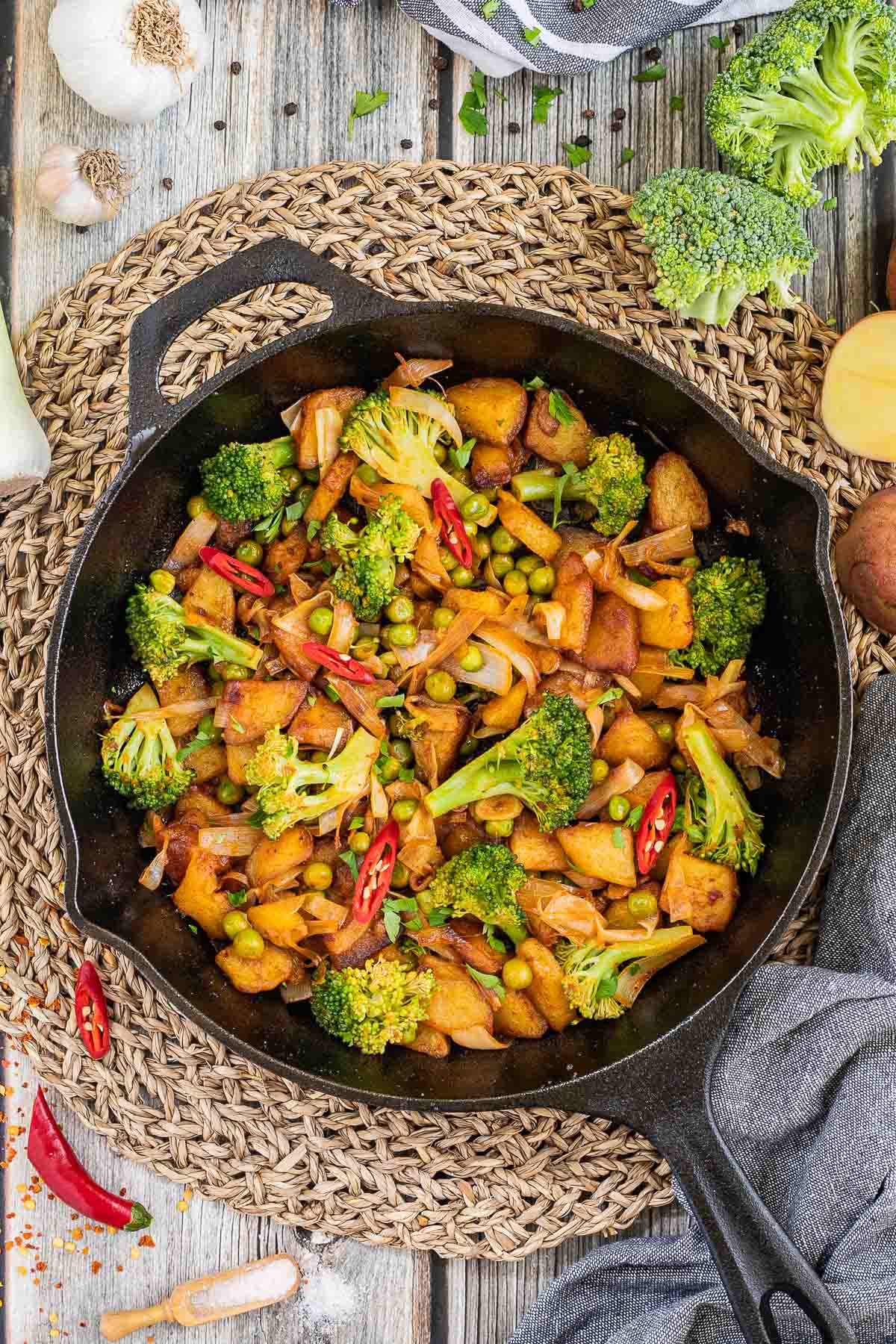 Skillet with potatoes, broccoli, chili peppers, green peas and onion. All slightly fried around the edges.