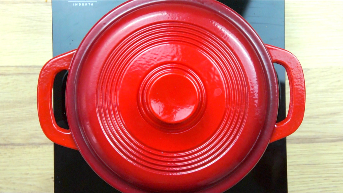 Red-white enameled Dutch oven with a lid on.