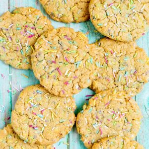 Light brown cookies with rainbow sprinkles on a blue wooden surface.