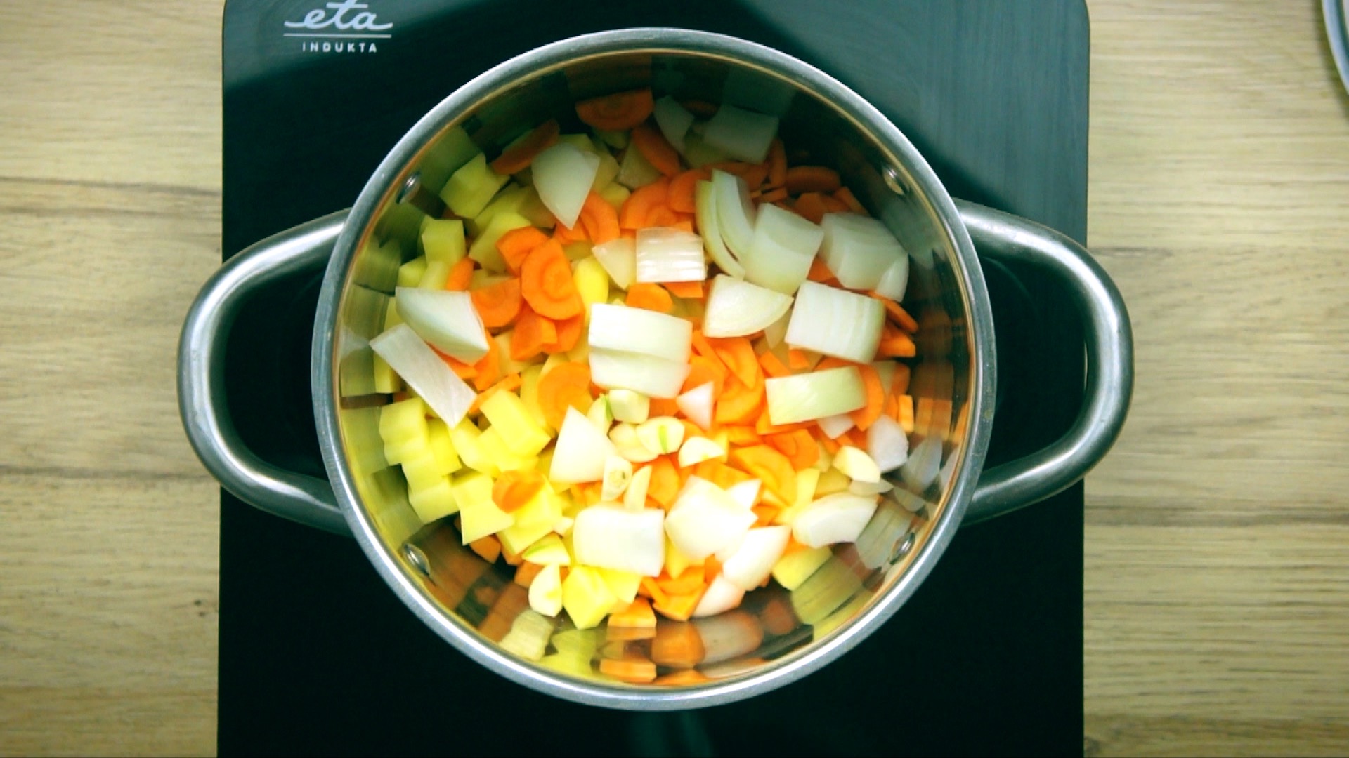 Stockpot with diced carrots, potatoes, orange sweet potatoes, onions and garlic.