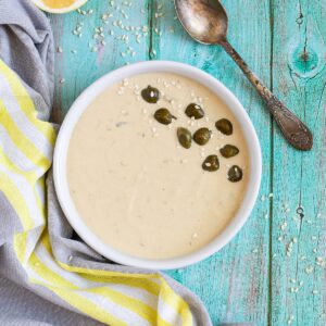 Small white bowl with a light brown thick sauce topped with sesame seeds and capers.